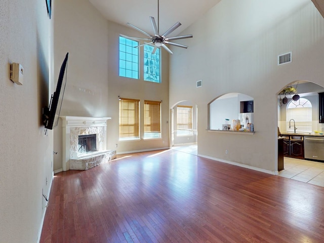 unfurnished living room with a premium fireplace, light hardwood / wood-style flooring, and a towering ceiling