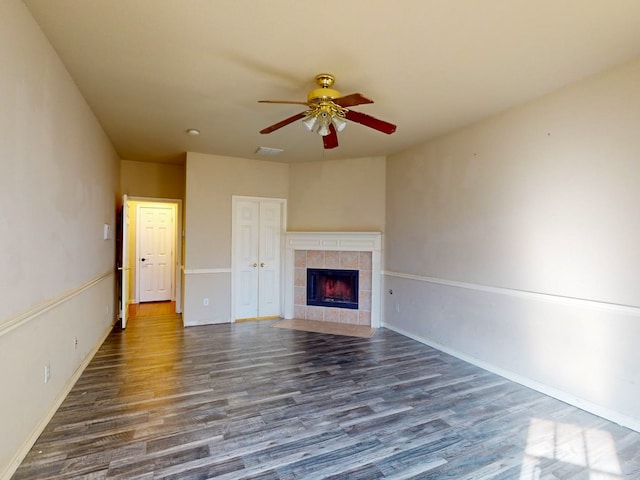 unfurnished living room with a tiled fireplace, ceiling fan, and dark hardwood / wood-style flooring