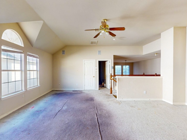 unfurnished living room with ceiling fan with notable chandelier, a healthy amount of sunlight, lofted ceiling, and light carpet