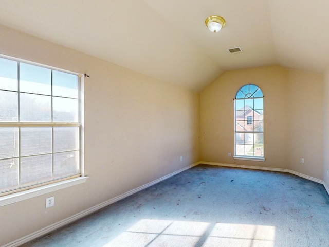 carpeted spare room with vaulted ceiling