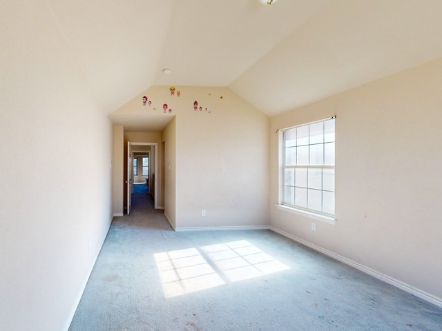 carpeted empty room featuring vaulted ceiling