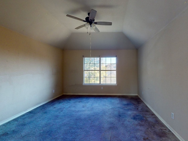 spare room featuring dark carpet, vaulted ceiling, and ceiling fan