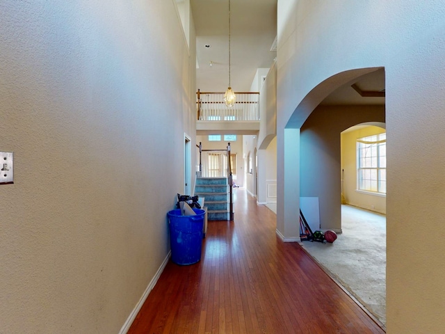 hallway with a towering ceiling and dark wood-type flooring