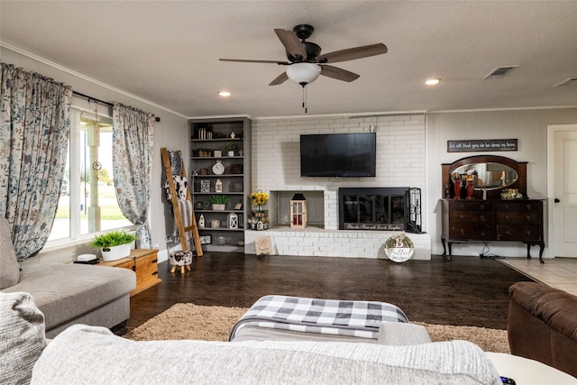 living room featuring ceiling fan, tile patterned flooring, crown molding, a textured ceiling, and a fireplace