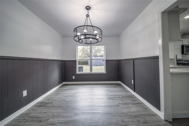 unfurnished dining area with an inviting chandelier and light hardwood / wood-style floors