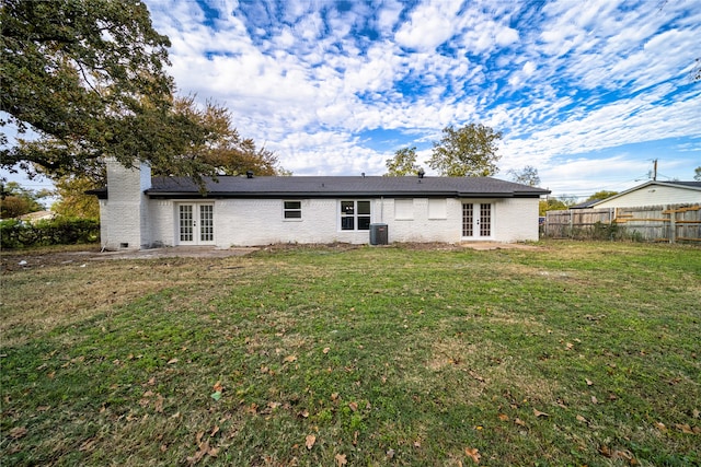 back of property featuring cooling unit, a lawn, and french doors