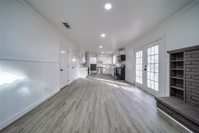 unfurnished living room featuring crown molding, light hardwood / wood-style floors, and french doors