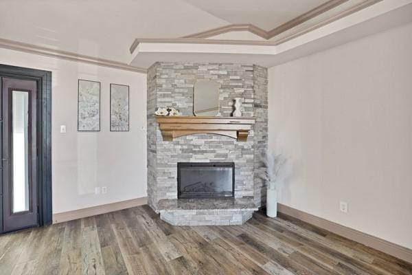 unfurnished living room with ornamental molding, wood-type flooring, a fireplace, and a tray ceiling