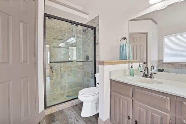 bathroom with hardwood / wood-style flooring, vanity, toilet, and a shower with door