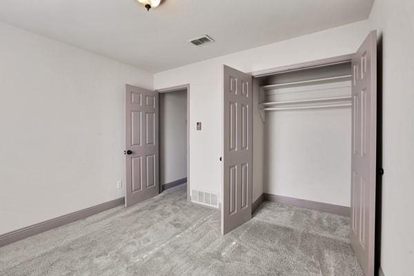 unfurnished bedroom with light carpet and a closet