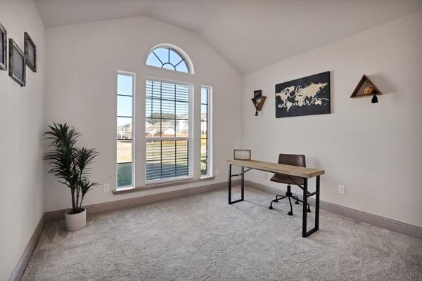 carpeted home office featuring lofted ceiling