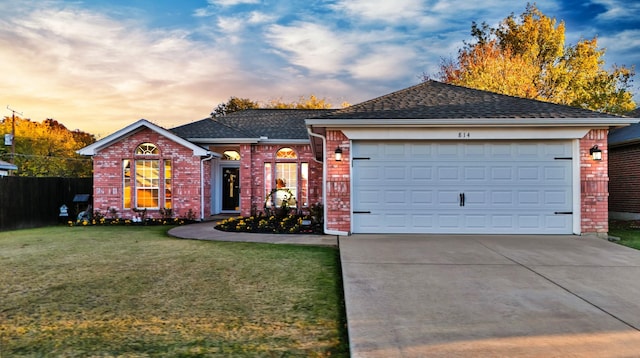 ranch-style home featuring a garage and a lawn