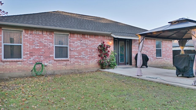 back of property featuring a gazebo, a patio, and a lawn