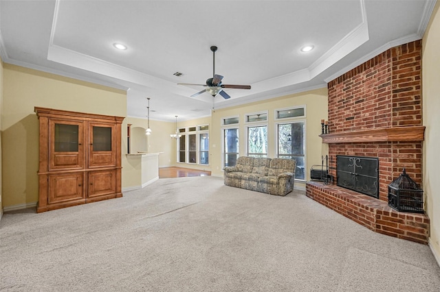 unfurnished living room featuring carpet floors, a tray ceiling, a fireplace, and visible vents