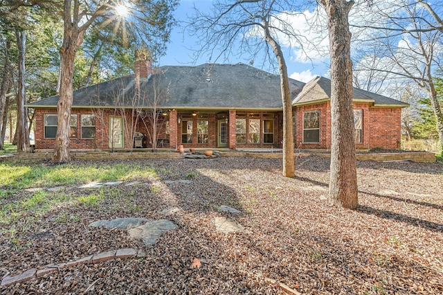 back of property featuring brick siding and a chimney