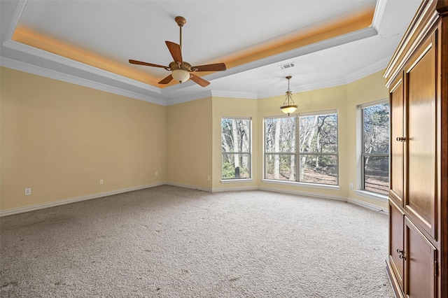 carpeted empty room featuring a tray ceiling, ceiling fan, and crown molding