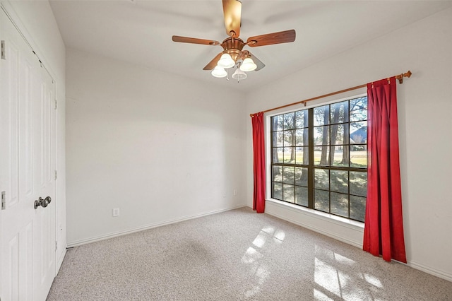 empty room featuring baseboards, a ceiling fan, and carpet flooring