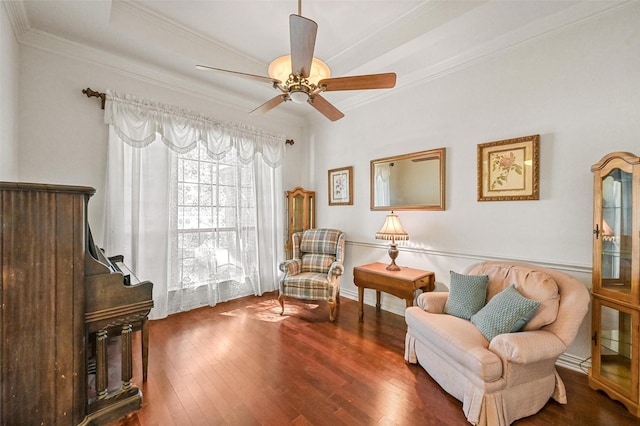 living area featuring dark hardwood / wood-style flooring, ceiling fan, and crown molding