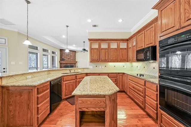 kitchen with kitchen peninsula, backsplash, black appliances, a center island, and hanging light fixtures