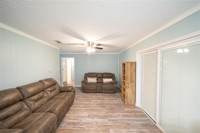 living room featuring a textured ceiling, light hardwood / wood-style floors, ceiling fan, and ornamental molding