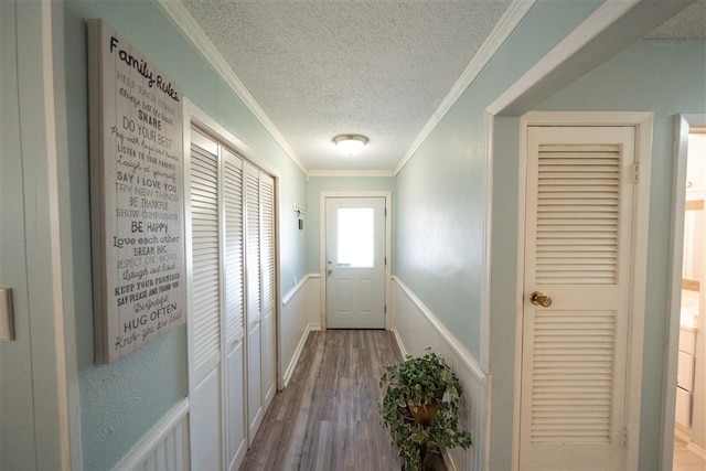 entryway with ornamental molding, a textured ceiling, and light hardwood / wood-style flooring