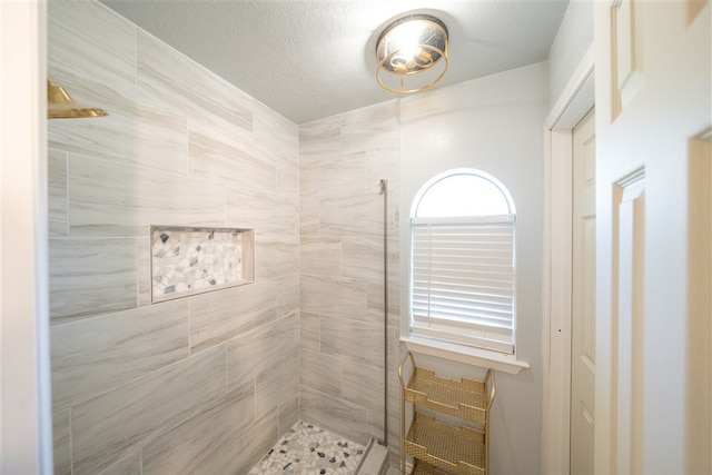 bathroom featuring a textured ceiling and tiled shower