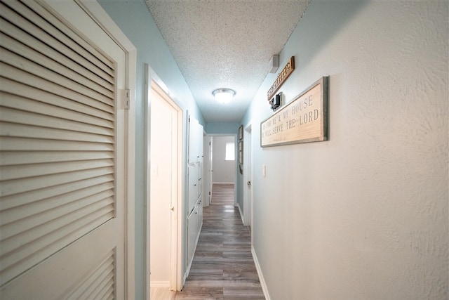 hallway with hardwood / wood-style flooring and a textured ceiling