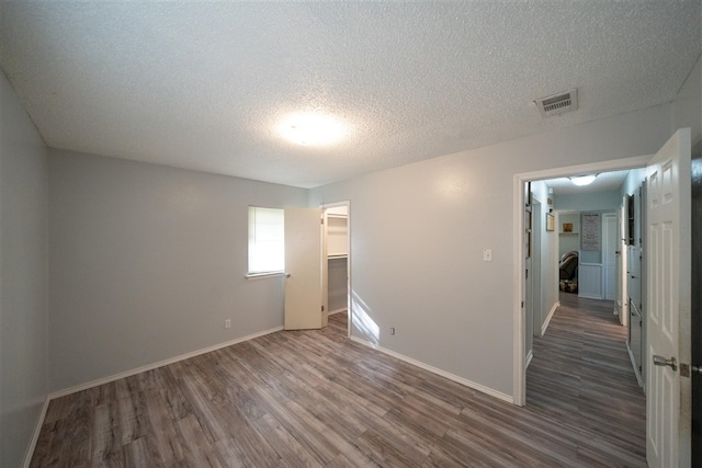 empty room featuring a textured ceiling and dark hardwood / wood-style floors