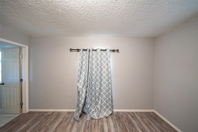 empty room featuring wood-type flooring and a textured ceiling