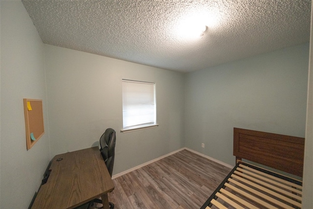 bedroom with a textured ceiling and hardwood / wood-style flooring