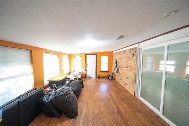 living room with hardwood / wood-style floors, brick wall, and a textured ceiling