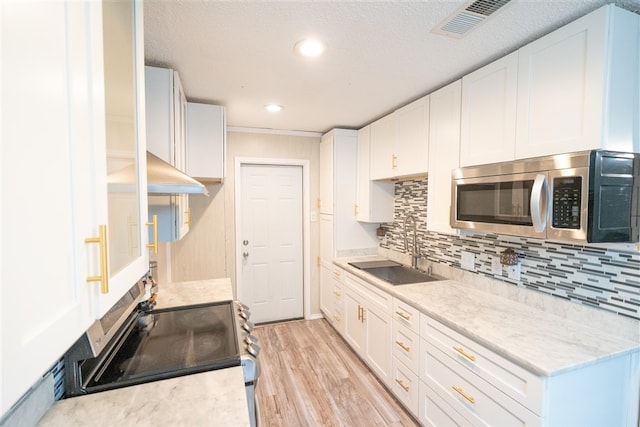 kitchen with sink, backsplash, range with electric stovetop, white cabinets, and light wood-type flooring