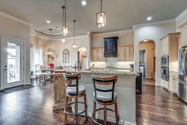 kitchen with decorative light fixtures, dark hardwood / wood-style flooring, stainless steel appliances, and a kitchen island with sink