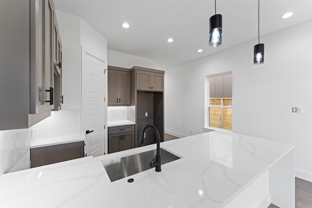 kitchen featuring light stone countertops, pendant lighting, hardwood / wood-style floors, and sink