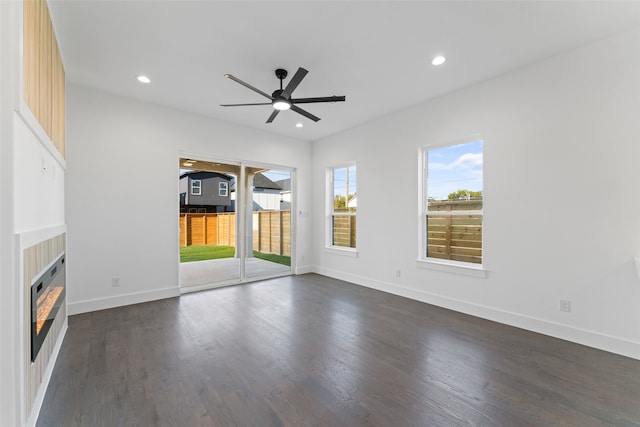 unfurnished living room with ceiling fan, a fireplace, and dark wood-type flooring