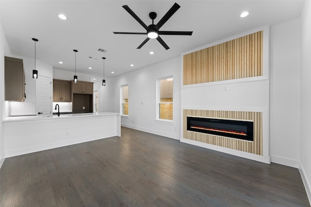 unfurnished living room featuring ceiling fan, sink, and dark wood-type flooring