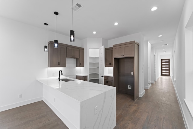 kitchen featuring sink, hanging light fixtures, dark hardwood / wood-style flooring, backsplash, and kitchen peninsula