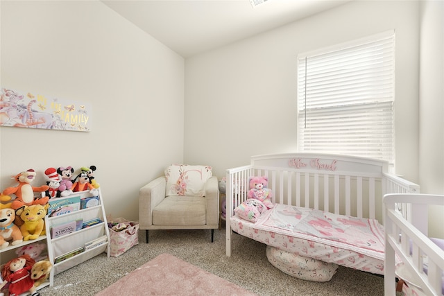 carpeted bedroom featuring a nursery area