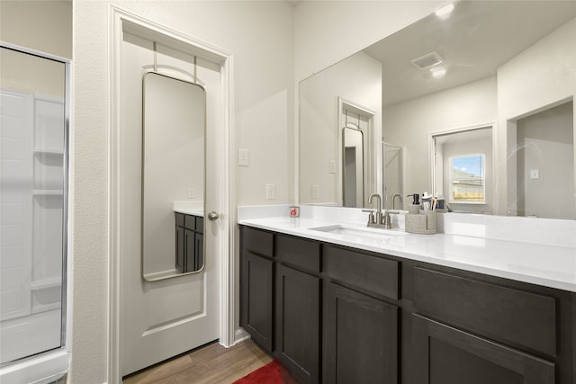 bathroom with hardwood / wood-style floors, vanity, and a shower with door