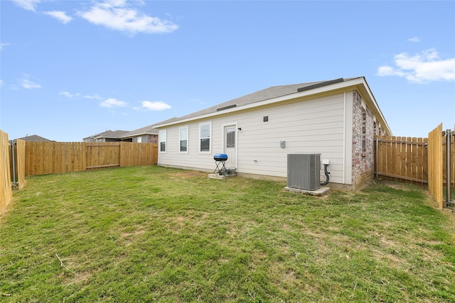 rear view of property with cooling unit and a lawn