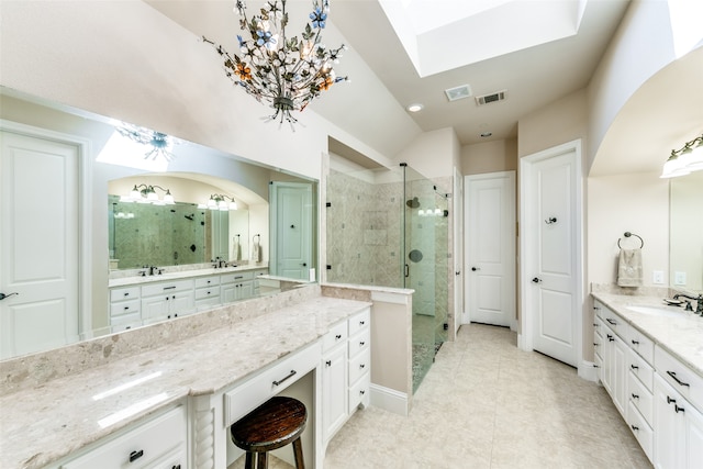 bathroom with tile patterned flooring, vanity, walk in shower, and a skylight