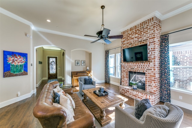 living room featuring a fireplace, wood-type flooring, ceiling fan, and crown molding