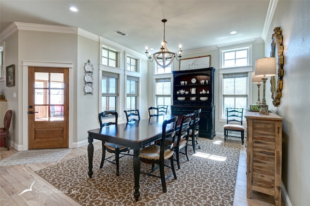 dining room featuring a healthy amount of sunlight, light wood-type flooring, and ornamental molding