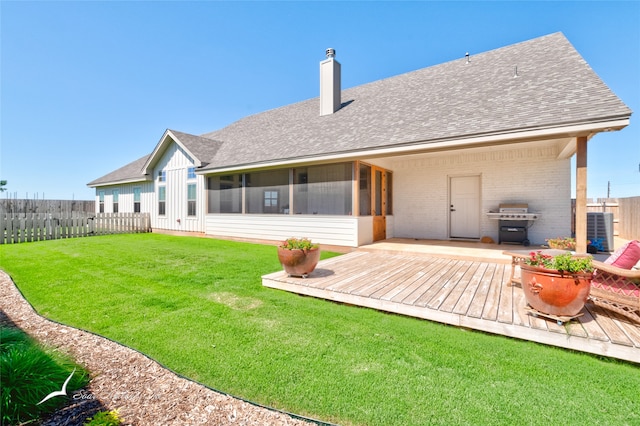 rear view of house with a sunroom, a deck, a yard, and central AC