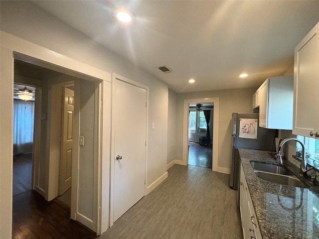 kitchen featuring dark stone countertops, white cabinetry, sink, and dark wood-type flooring