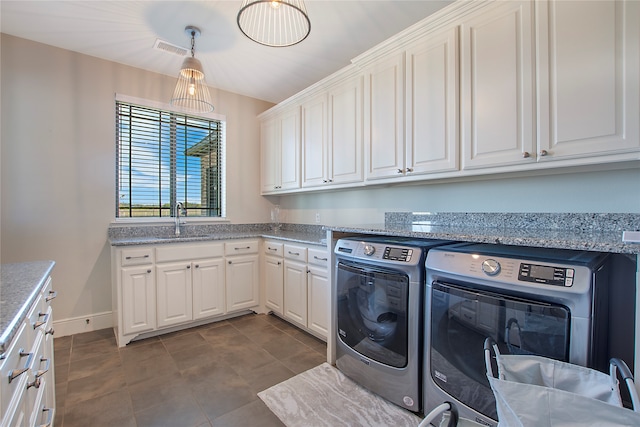 clothes washing area with washing machine and dryer, sink, and cabinets