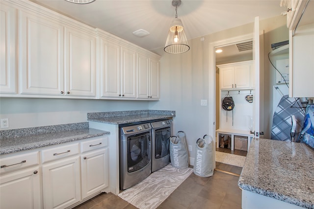 clothes washing area featuring cabinets, washing machine and dryer, and tile patterned floors