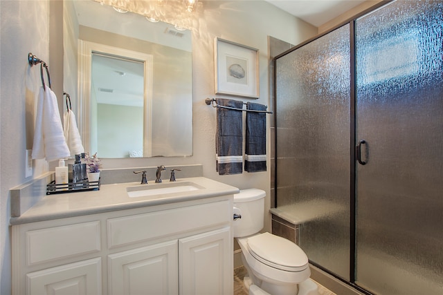 bathroom with vanity, a shower with shower door, and toilet