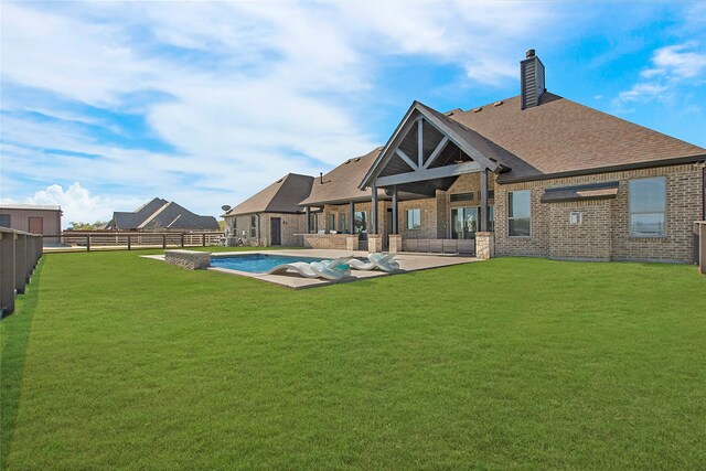 rear view of property featuring a fenced in pool, a yard, and a patio