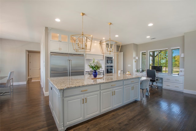 kitchen with white cabinetry, dark hardwood / wood-style flooring, an island with sink, and stainless steel appliances